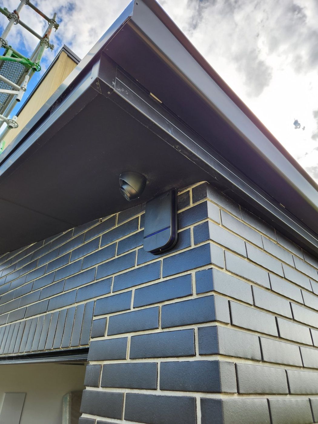 Dome camera and alarm siren tucked under the eave