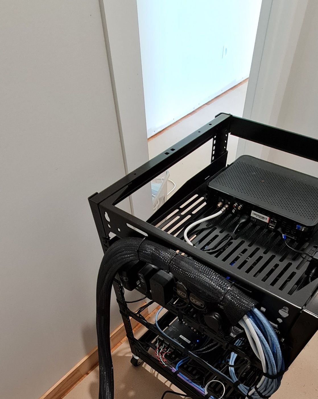 AV rack with cabling bundled and sleeved down to the wall plate